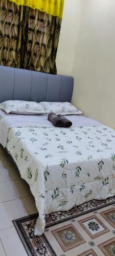 a bed with a white blanket with leaves on it at Homestay Kasih KandAdinda in Kampung Gurun