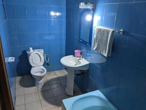 niebieska łazienka z toaletą i umywalką w obiekcie Hotel Bella Vida w mieście Lomé