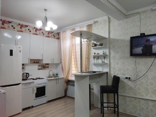 una cucina con armadi bianchi e una TV a parete di Аренда квартиры a Balqash