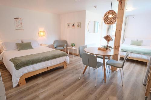 een slaapkamer met een bed en een tafel en stoelen bij AUBERGE DU DIMANCHE - Riviere-Eternite, Pres du Fjord-du-Saguenay et de l'Anse-Saint-Jean in Riviere Eternite