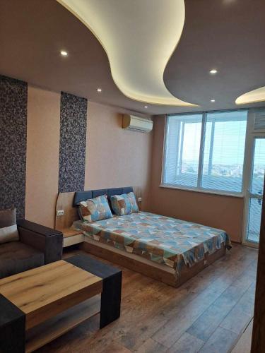 een slaapkamer met een bed en een bank in een kamer bij Луксозен апартамент с гледка към парк и център in Yambol