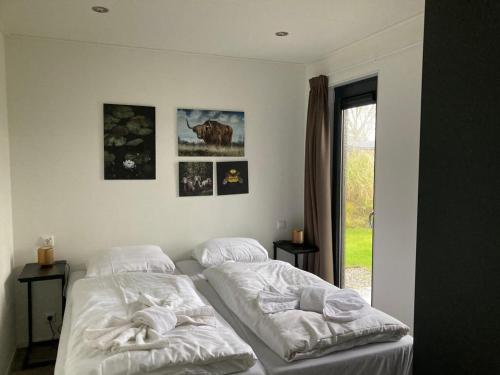 a bedroom with two beds and a window at 6 persoons bungalow met omheining van de tuin vlakbij Walibi in Biddinghuizen