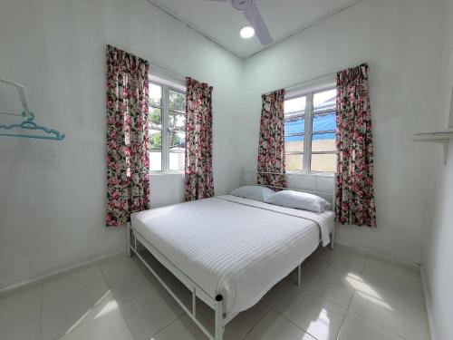 a small bedroom with a bed and two windows at Cantik-La Homestay Kolam 3 Bilik Kuala Terengganu in Bukit Payong