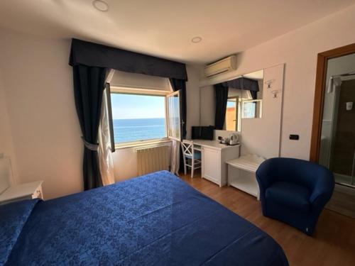 Schlafzimmer mit einem blauen Bett, einem Schreibtisch und einem Fenster in der Unterkunft Hotel L'Isola in Santa Marinella