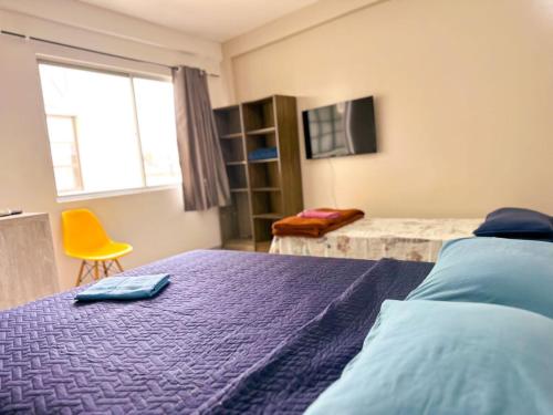 sypialnia z fioletowym łóżkiem i żółtym krzesłem w obiekcie Hotelcity w mieście Brusque