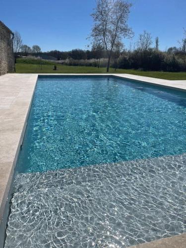 une piscine avec de l'eau bleue dans une cour dans l'établissement Villa Fongrive, ferme Périgourdine haut de gamme, à Thénac