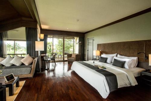 Cette chambre comprend un grand lit et un canapé. dans l'établissement Maneechan Resort - SHA Extra Plus, à Chanthaburi