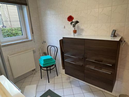 a bathroom with a cabinet and a chair and a window at Appartement Am Weinberg in Radebeul