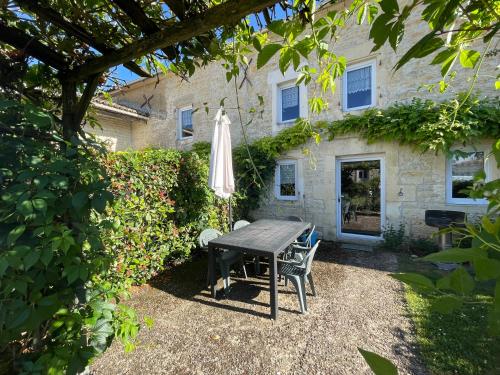a table and chairs and an umbrella in front of a house at Les Constellations, 8 gite complex, 53 people, marriage, birthday, etc in Doeuil-sur-le-Mignon