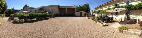 a dirt road with a building and an umbrella at Les Constellations, 8 gite complex, 53 people, marriage, birthday, etc in Doeuil-sur-le-Mignon