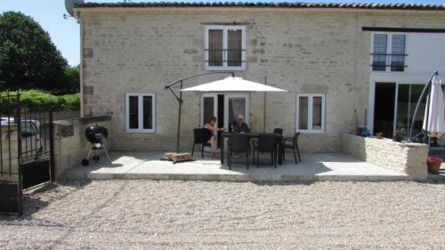 a man and woman sitting at a table under an umbrella at Les Constellations, 8 gite complex, 53 people, marriage, birthday, etc in Doeuil-sur-le-Mignon