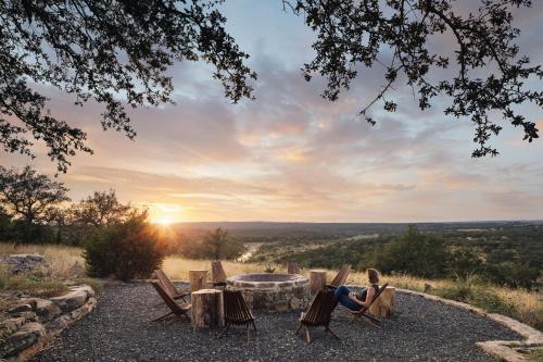 a woman sitting in chairs around a table with the sunset at Walden Retreats Hill Country in Johnson City