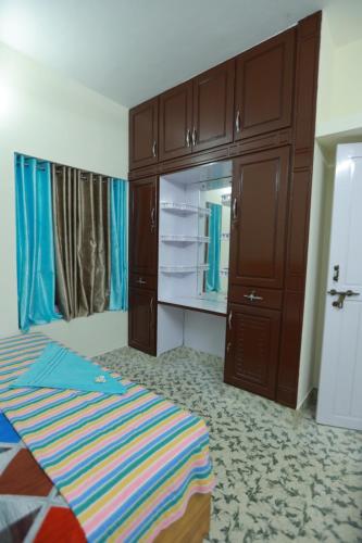 a bedroom with a bed and wooden cabinets and a mirror at Ritu Homestay in Trivandrum