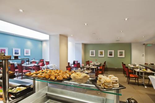 a buffet line with bread and pastries in a restaurant at Gem Langham Court Hotel in London
