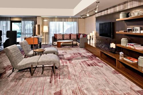 a living room with a couch and chairs and a tv at Courtyard by Marriott Charlotte Ballantyne in Charlotte