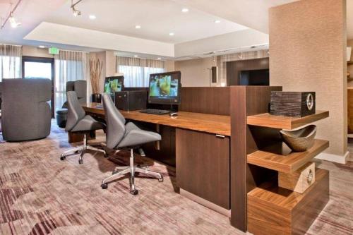 an office with a desk with a computer and two chairs at Courtyard by Marriott Charlotte Ballantyne in Charlotte