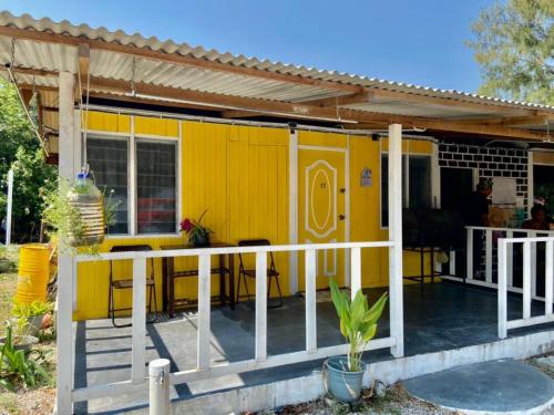 a yellow tiny house with a porch at Global Star Chalet in Kampong Batang Tiga