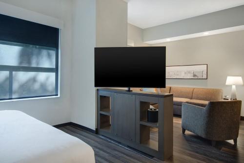 a bedroom with a flat screen tv and a couch at Hyatt House Mall Of America Msp Airport in Bloomington