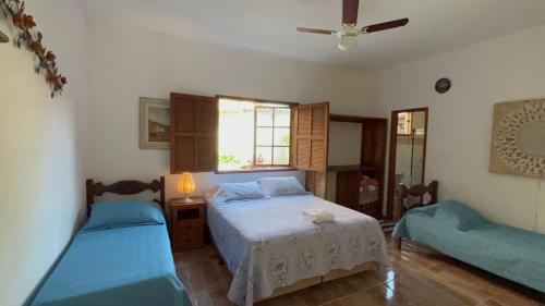 Un dormitorio con dos camas y una ventana. en JPK Guest House, en Tiradentes
