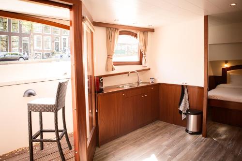 una pequeña cocina con fregadero y un dormitorio en Prinsenboot, en Ámsterdam