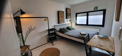 1 dormitorio con cama, escritorio y ventana en Bij Sarah, en Leopoldsburg