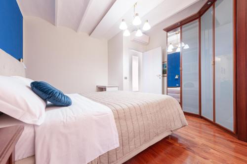 a white bedroom with a large white bed with blue pillows at Maison Indipendenza in Bologna