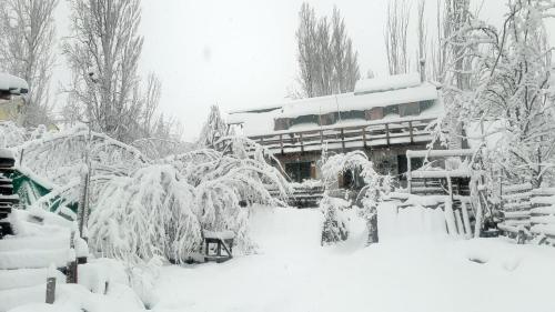 a garden covered in snow with a building in the background at Hostal Crisol in Lo Valdés