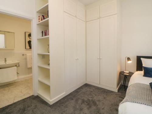 um quarto com armários brancos, uma cama e um lavatório em Brompton Gardens em Torquay