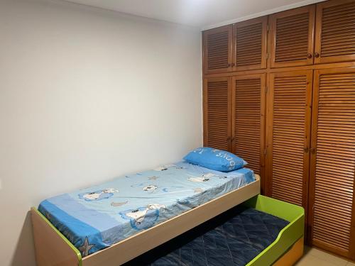 a small bedroom with a bed and wooden cabinets at Piso cerca de la playa. in Melilla