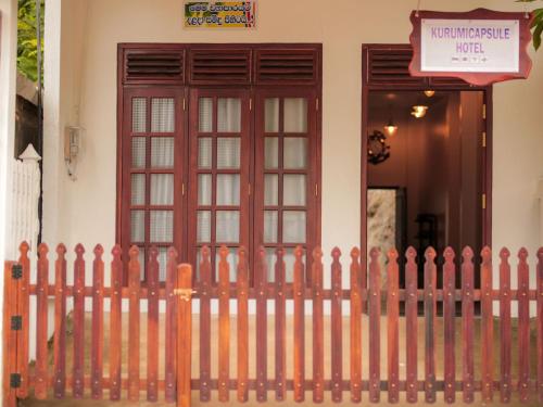 a fence in front of a house with a door at Kurumi Capsule Hotel in Weligama