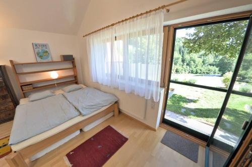 a small bedroom with a bed and a large window at Holzhäuschen mit Pool 