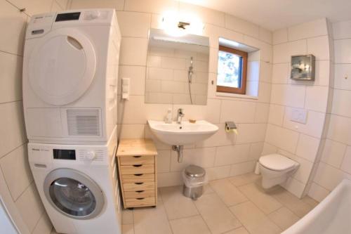 een badkamer met een wasmachine en een wastafel bij Holzhäuschen mit Pool 