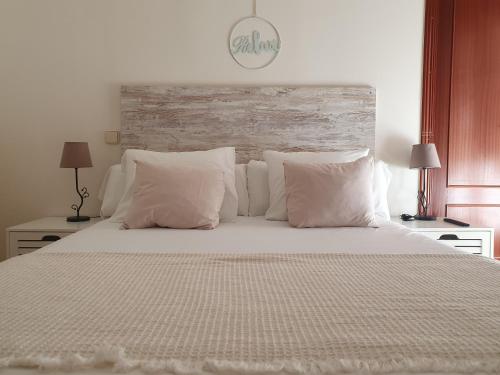 a bedroom with a large bed with white sheets and pillows at ToledoRooms Palacios in Toledo