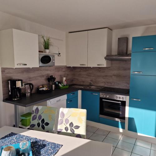 a kitchen with white cabinets and blue appliances at Ferienwohnung Vier Pfoten in Willingen