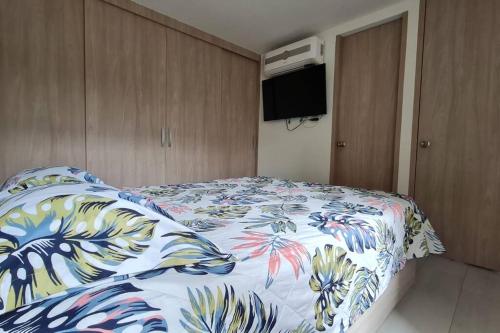 a bedroom with a bed with a floral bedspread at Apartamento en Guabinas Yumbo 