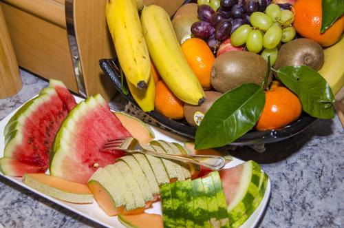 a plate of fruit with bananas apples oranges and grapes at Hotel Garni Alpenhof in Ischgl