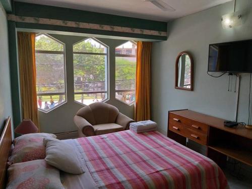 a bedroom with a bed and a chair and windows at Hotel el sol in Chiclayo