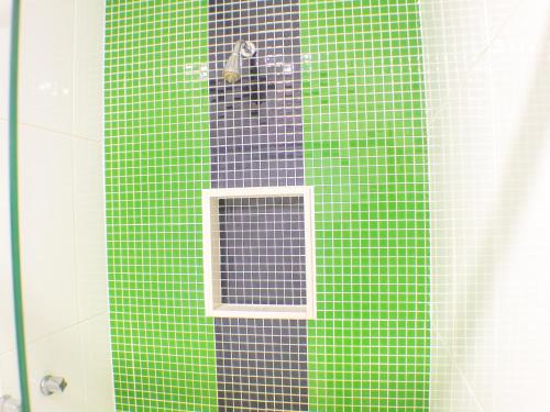 a glass shower with a window on a green wall at Condor Hotel in Rio de Janeiro