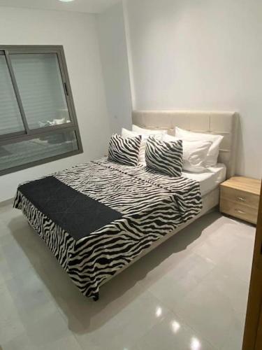 1 cama con sábanas de cebra y almohadas en una habitación en Dar Kmar, en Túnez