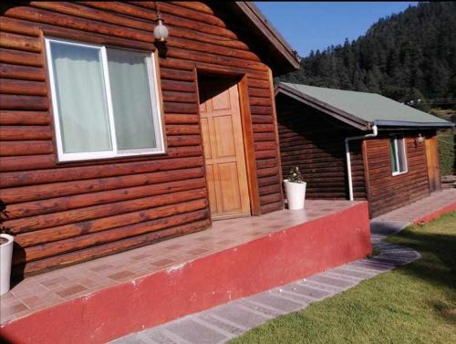 Cabaña de madera con puerta y porche en Posada El Roble. en Ciudad de México