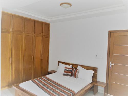 a bedroom with a bed and wooden cabinets at Les Residences de la Diaspora in Dakar