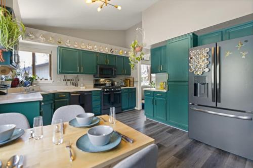 una cocina con armarios verdes y una mesa con platos. en Stylish Home with in Home Gym AC Fully Fenced Yard, en Flagstaff