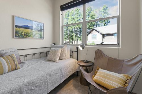 a bedroom with a bed and a chair and a window at The Sage Wood House in Flagstaff