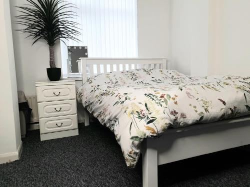 a bedroom with a bed with a plant and a nightstand at The Quiet Room in Newcastle upon Tyne