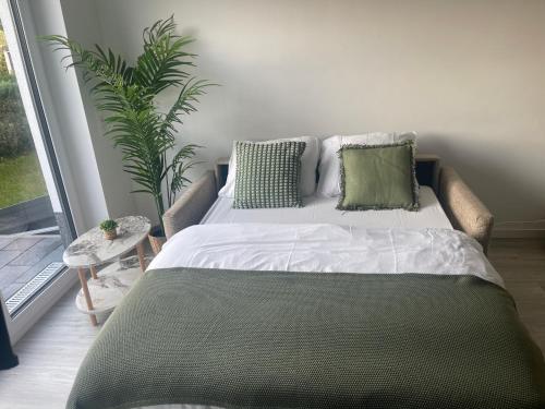 a bed with green pillows in a room with a plant at Modernes und helles Mini-Haus in Peine in Peine