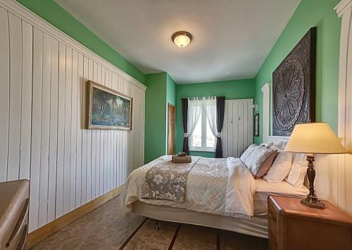 a bedroom with green walls and a bed with a lamp at Maison Zacharie in Desbiens