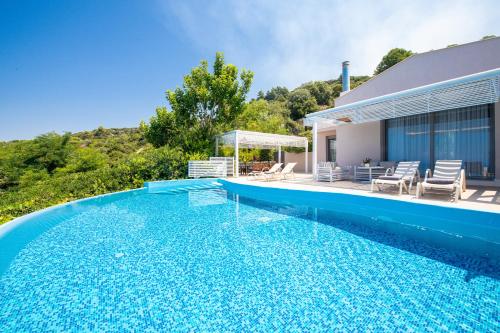 a swimming pool in front of a house at Mare Dei Suites Hotel Ionian Resort in Skafidia