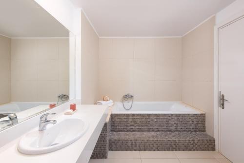 a white bathroom with a tub and a sink at Mare Dei Suites Hotel Ionian Resort in Skafidia