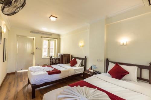 Habitación de hotel con 2 camas con almohadas rojas en Hotel Highlander, Thamel, en Katmandú