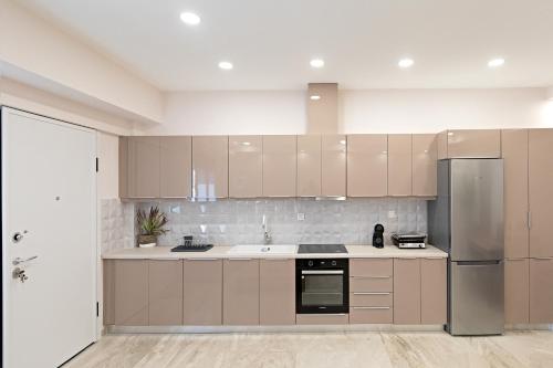 a kitchen with beige cabinets and a stainless steel refrigerator at Garden Apartment in Amarynthos II in Amarynthos